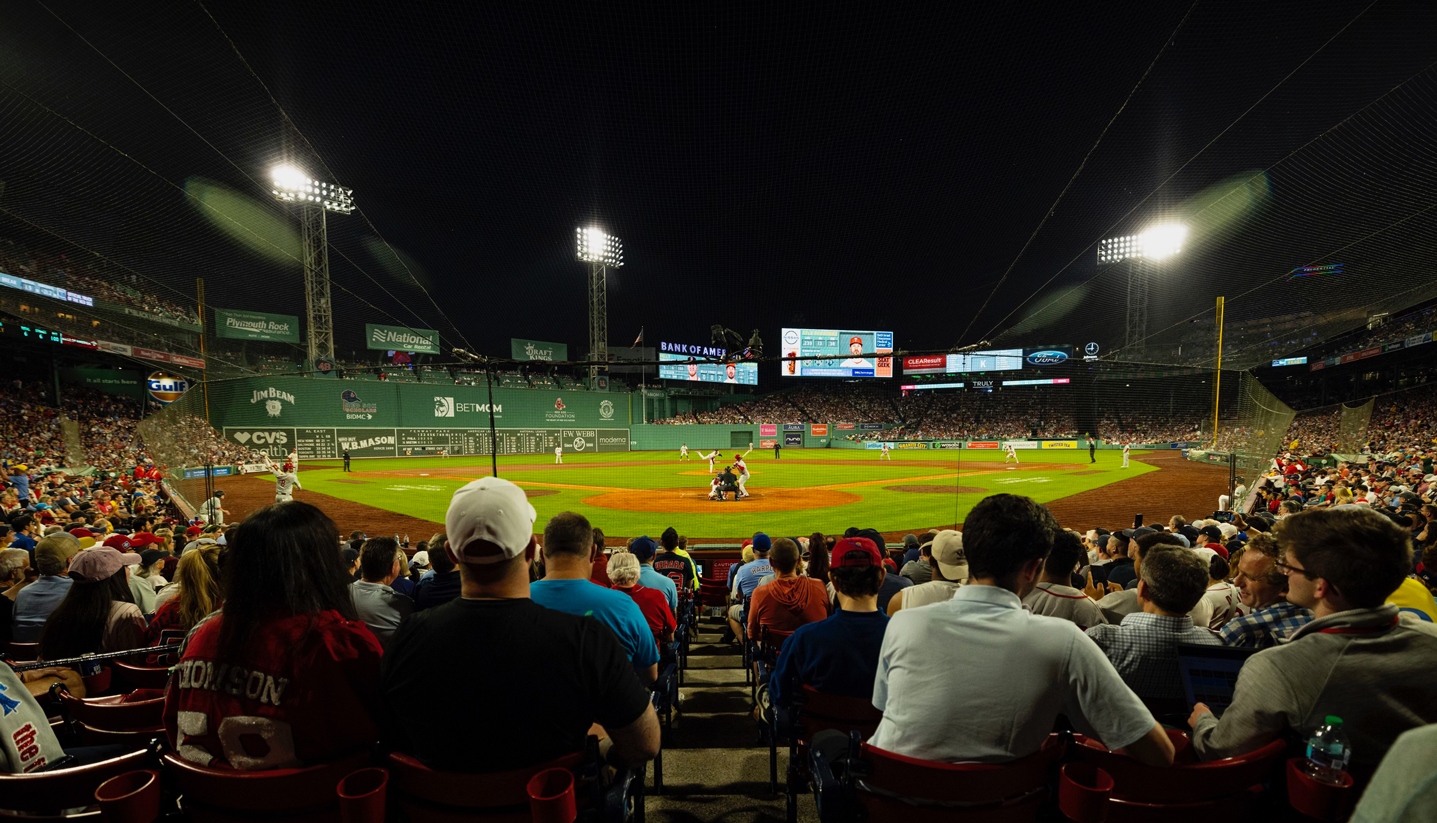 A view of Fenway Park™ from the seats behind home plate as the pitcher throws the ball