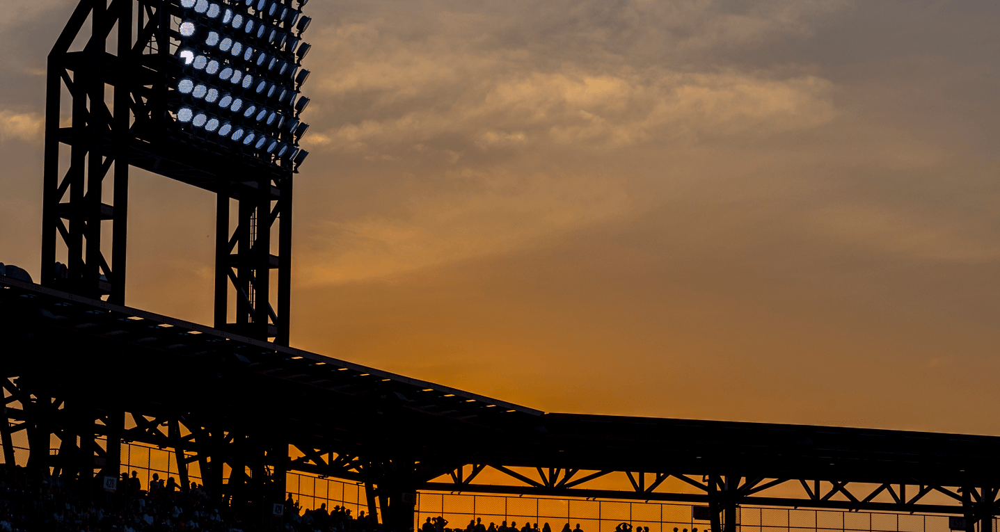 Stadium lights silhouetted by a sunset